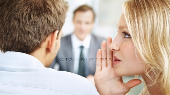 Woman whispering in the ears of the business man with their leader in background